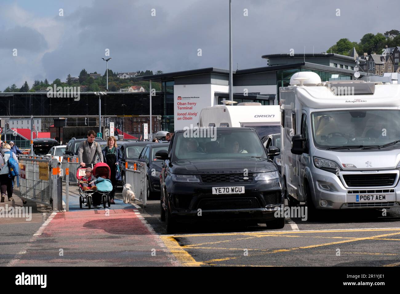 Oban, Scotland, UK. 16th May 2023.  A hive of activity at the Ferry terminal with passengers embarking Calmac ferries to the Hebridean Isles and disembarking back to the mainland. Cars queued up waiting to board ferry MV Loch Frisa for the journey to Craignure on the Isle of Mull. Credit: Craig Brown/Alamy Live News Stock Photo