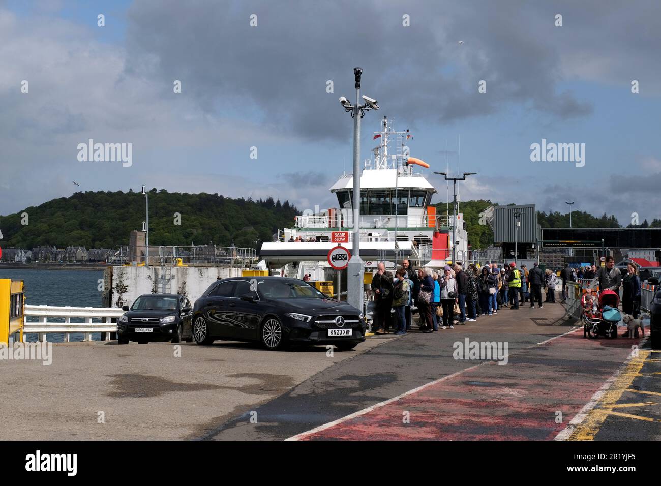 Oban, Scotland, UK. 16th May 2023.  A hive of activity at the Ferry terminal with passengers embarking Calmac ferries to the Hebridean Isles and disembarking back to the mainland. Cars disembarking the ferry and foot passengers waiting to board. MV Loch Frisa ferry operates a service between Oban and Craignure on the Isle of Mull. Credit: Craig Brown/Alamy Live News Stock Photo