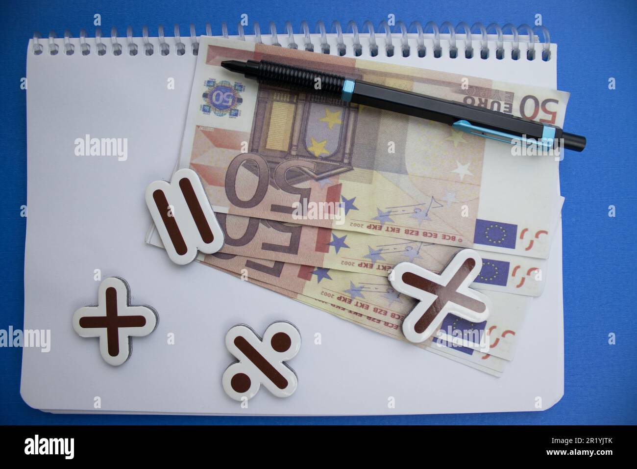 Placed on a blue background, notebook, euros, pencil and math signs. Stock Photo
