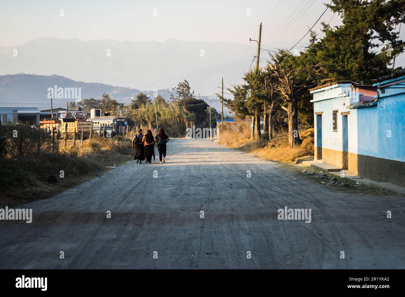 Three people making their way along a street in a rural setting Stock ...