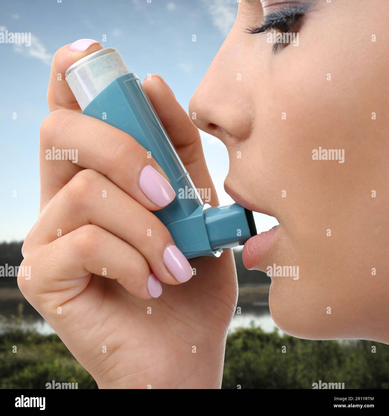 Woman using asthma inhaler, closeup. Emergency first aid during outdoor recreation Stock Photo