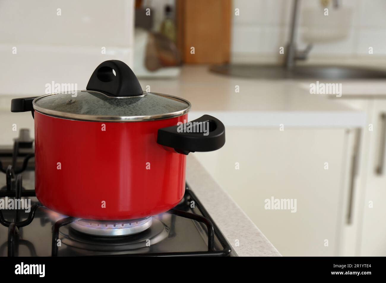 https://c8.alamy.com/comp/2R1YTE4/red-pot-on-modern-kitchen-stove-with-burning-gas-space-for-text-2R1YTE4.jpg