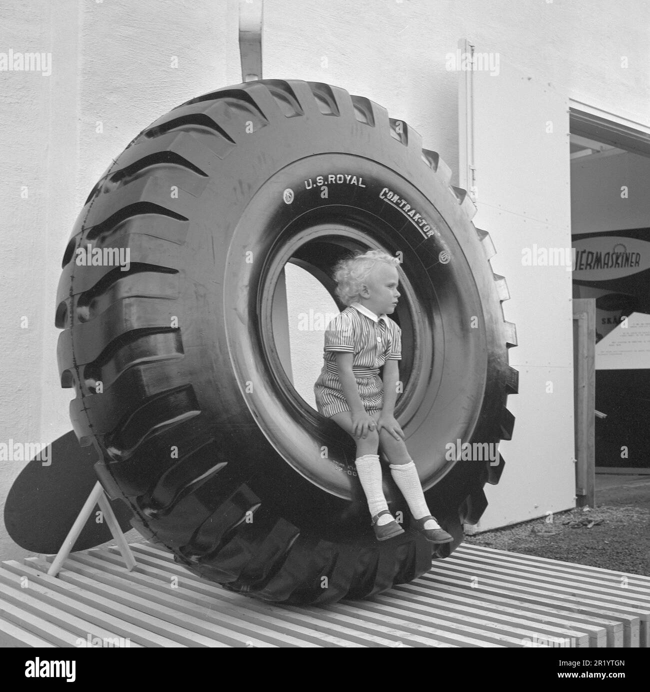 In the 1950s. A little boy is sitting on a giant tire displayed on the exhibition Sankt Eriks-mässan in Stockholm 1950. An exhibition showing the latest 1950s products for the public. Sweden 1950. Conard ref 1453 Stock Photo