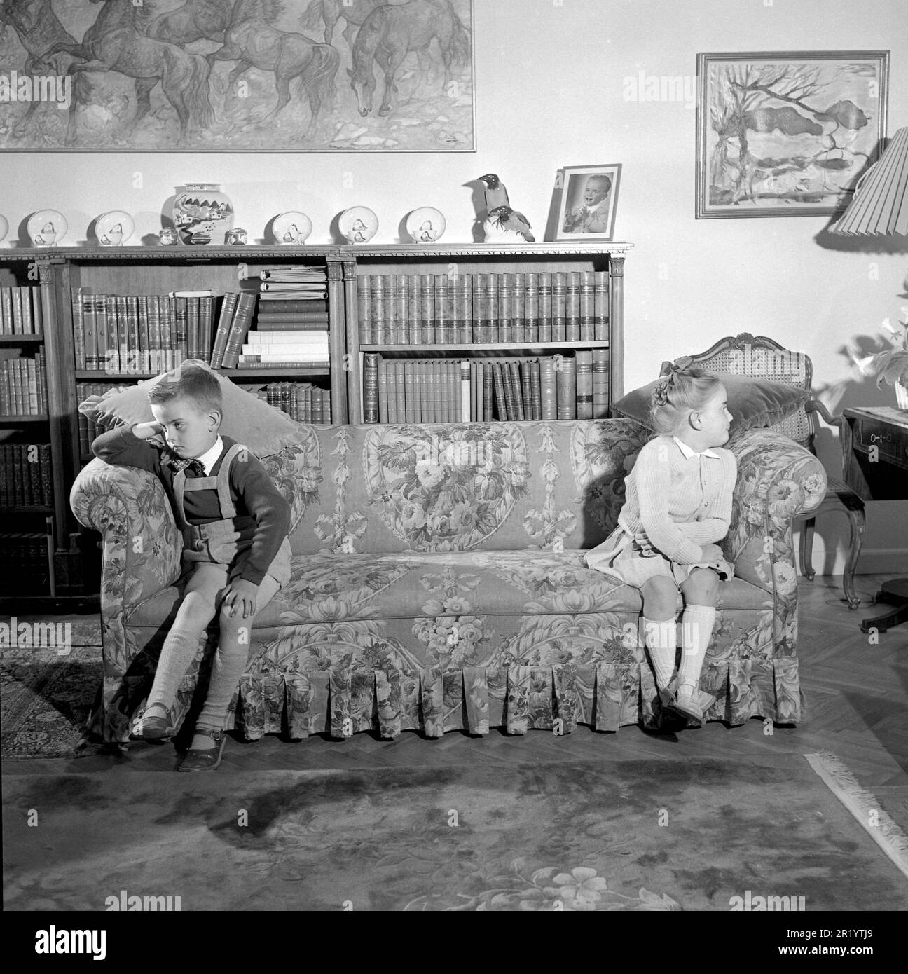 In the 1950s. Two children are sitting at the far ends of the sofa, visibly angry and upset with each other, not willing to make friends. Conard ref 1716 Stock Photo