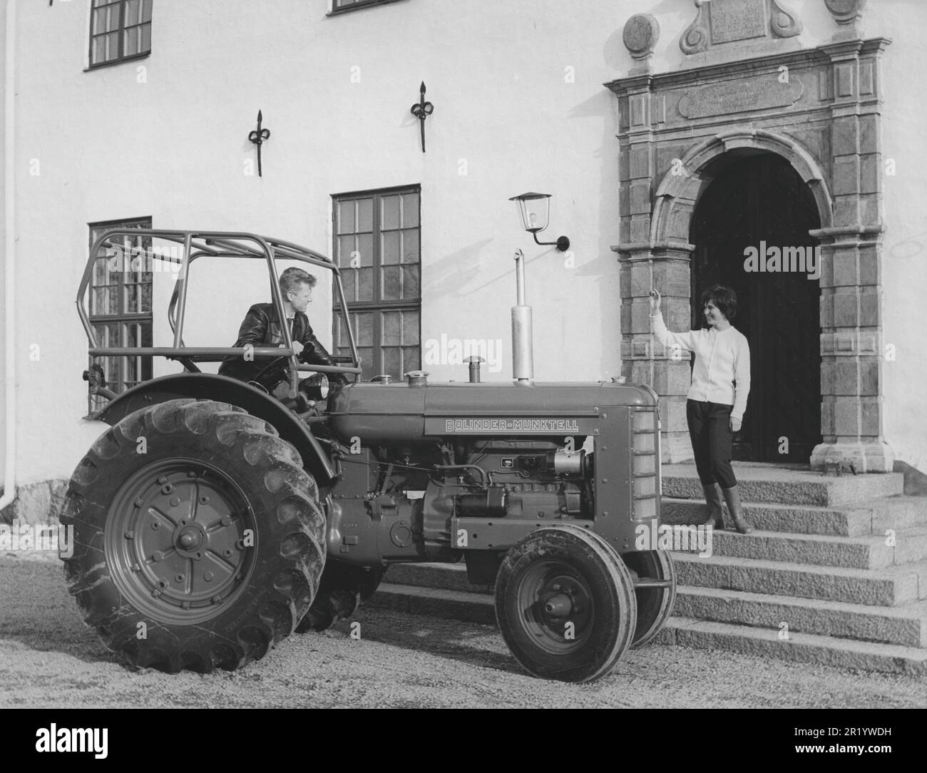 Farming in the 1950s. The new BM-Volvo tractor Bison is presented and launched as one of the world's largest wheeled tractors with a 4-cylinder diesel engine with an engine output of approx. 70 hp. The model was manufactured between the years 1959-1966. The man has driven up to the front door of a residence where a woman stands waving at him. Sweden 1959 Stock Photo
