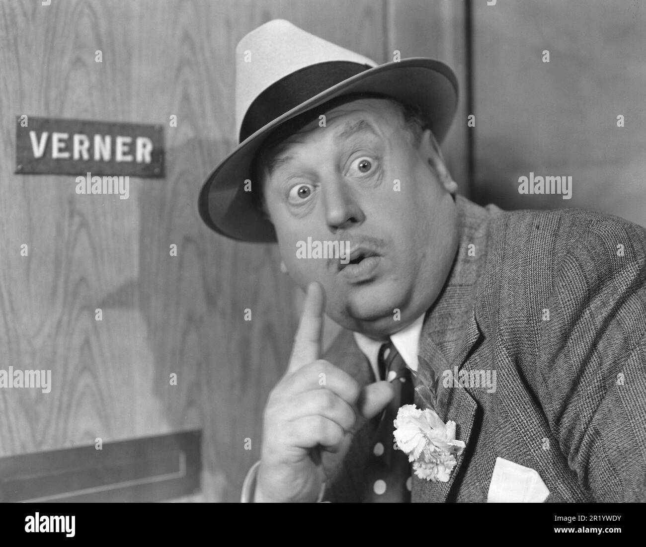 Secretive in the 1940s. Actor Thor Modéen pictured while acting in the movie 'Tåget går klockan 9'. Making the sign with his finger, perhaps to silence someone and to be able to listen to what they are saying on the other side of the door he stands in front of. Sweden 1941 Stock Photo