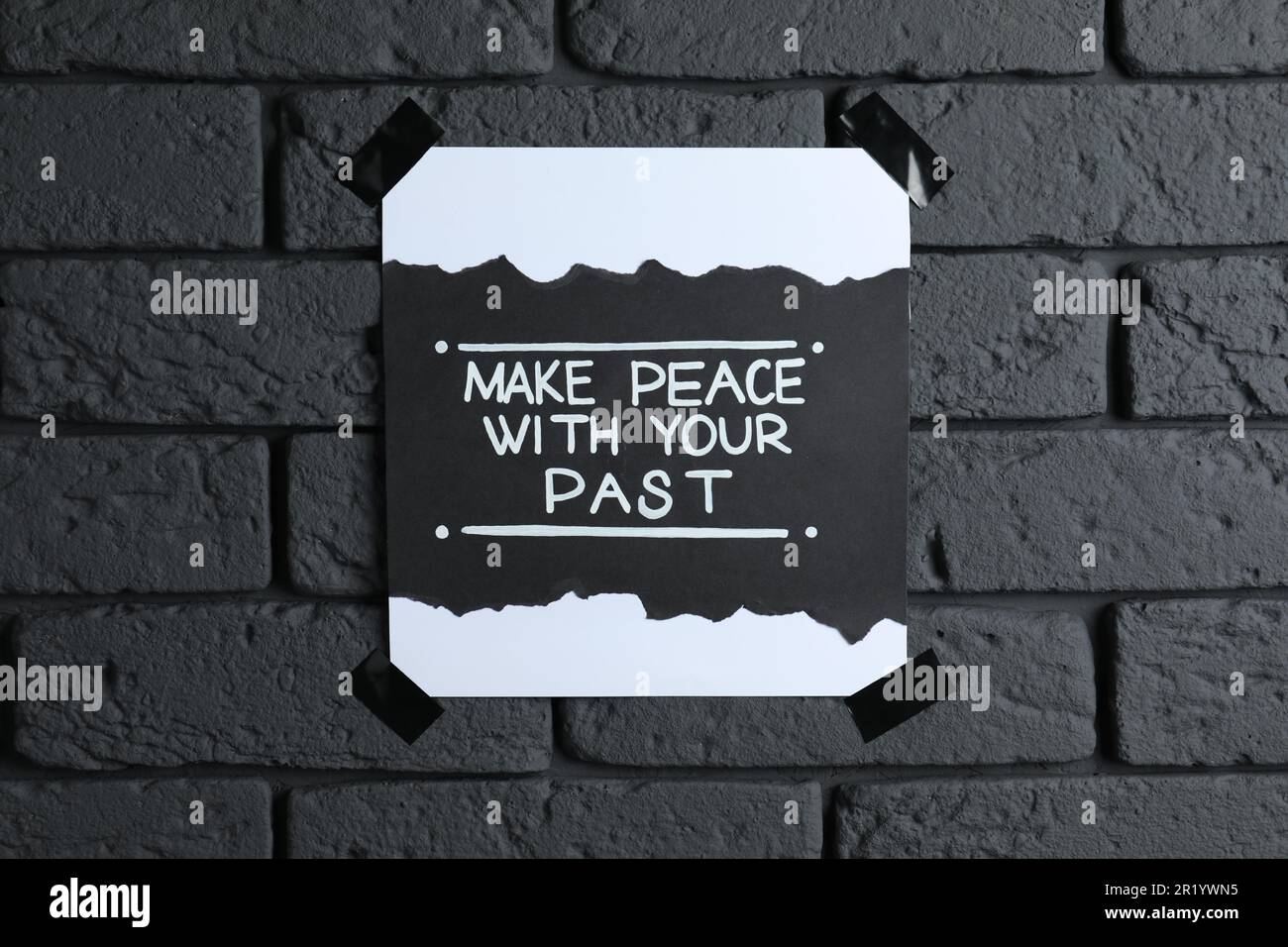 Card with life-affirming phrase Make Peace With Your Past on dark brick wall Stock Photo