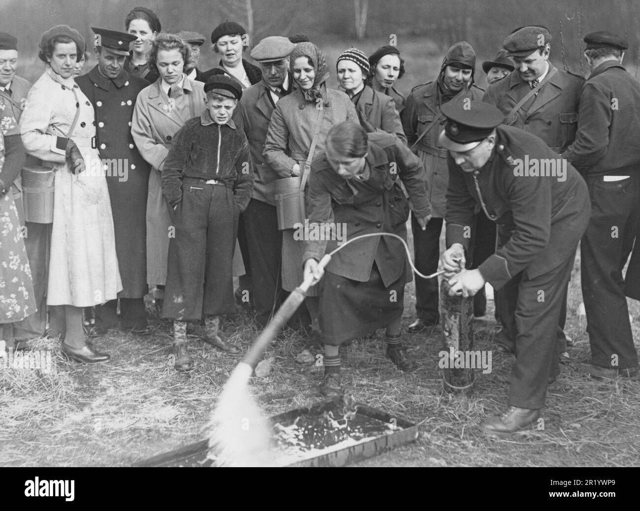 Preparations for wartime. The year is 1939 and Sweden is strenghtening it's civilian community and holds courses so people can act swifly when there is a fire. This in view of the talk of war in Europe and the encreased risk of sweden being involved in the war.  Pictured a member of the air defence organization that instructs how to use a fire extinguisher. Stockholm 27 april 1939. Stock Photo