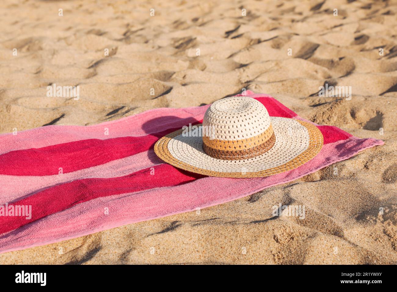 Beach towel and straw hat on sand Stock Photo - Alamy