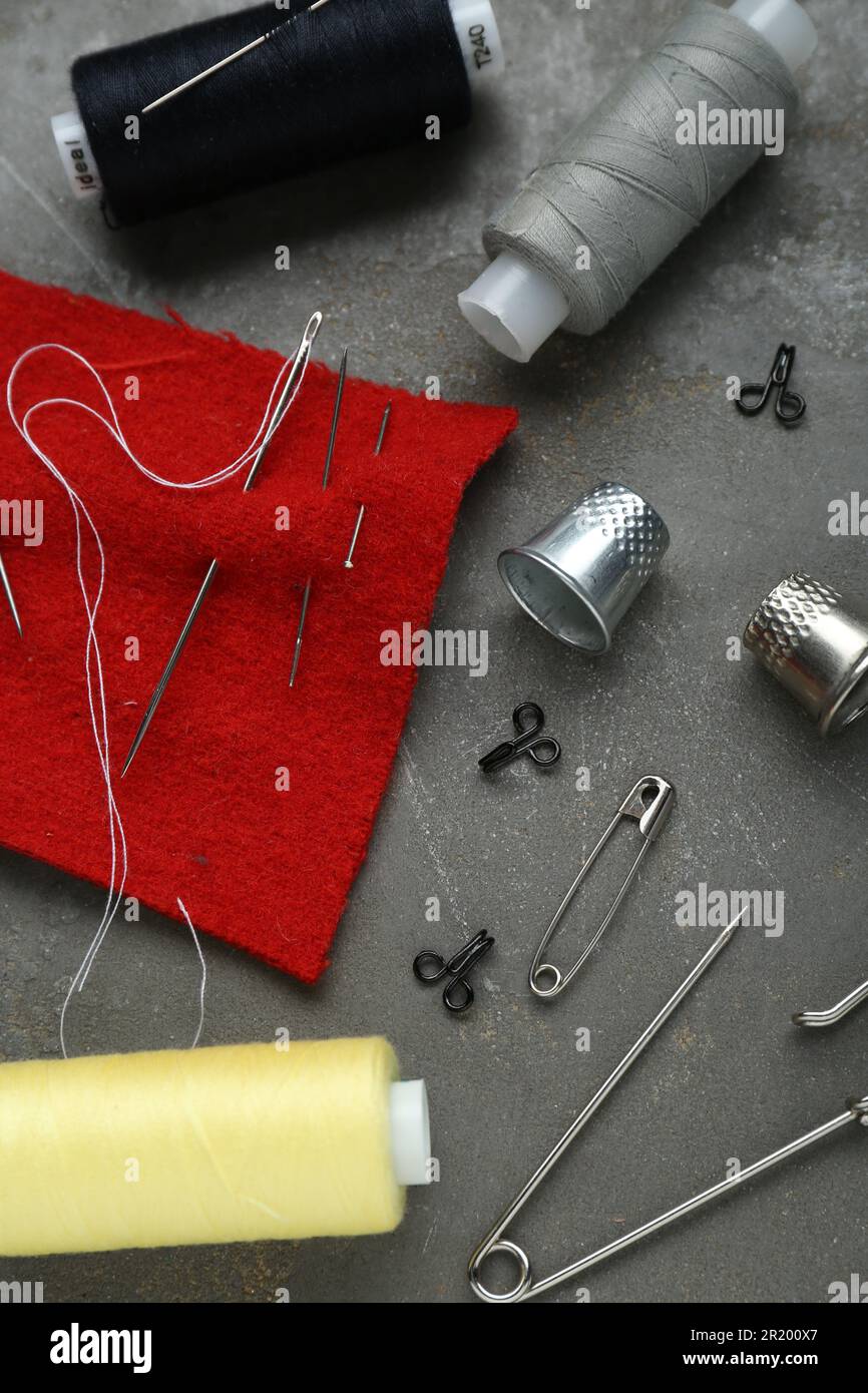 Flat lay composition with thimbles and different sewing tools on grey table Stock Photo