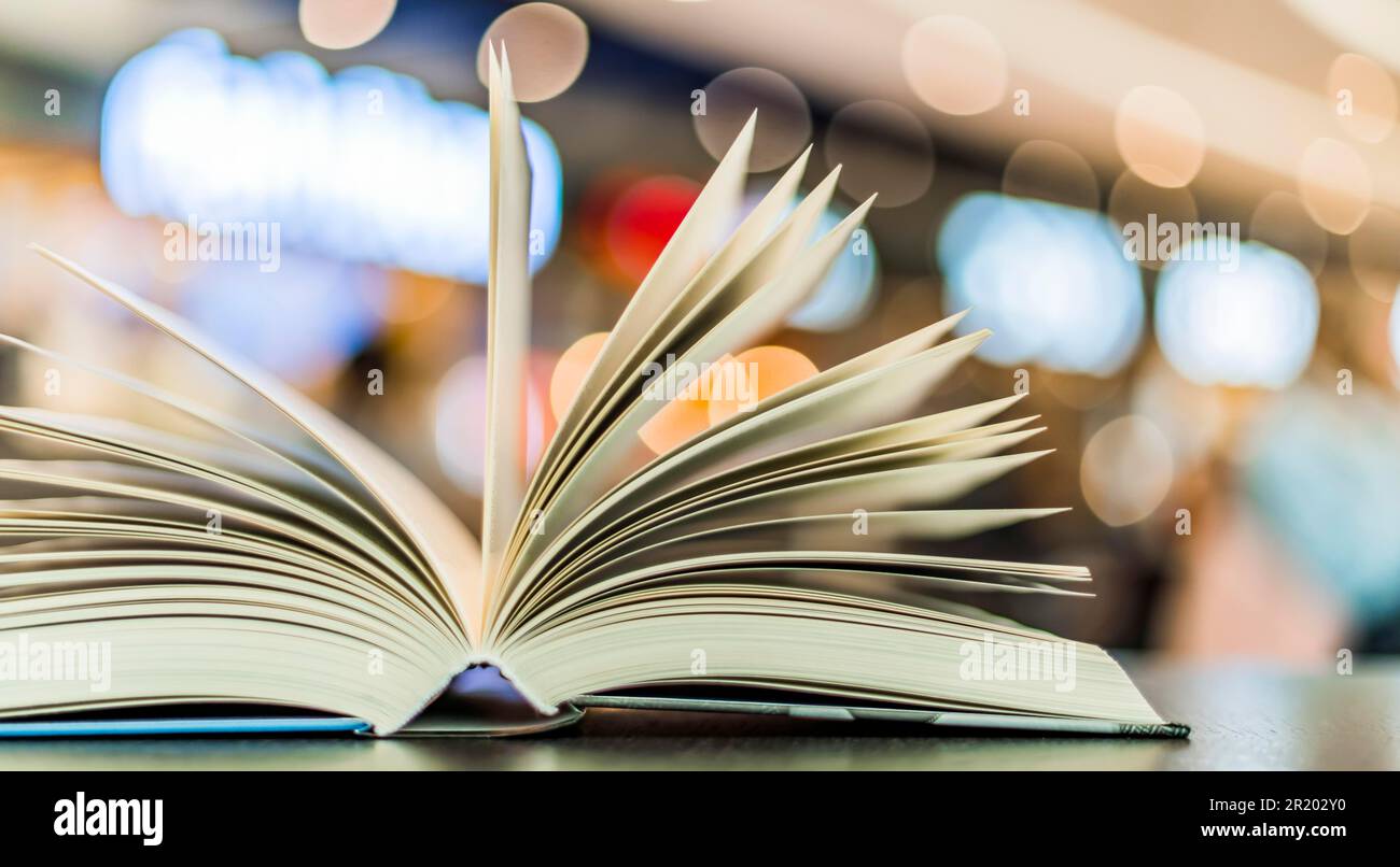 An open hardcover book on a table in a public library Stock Photo