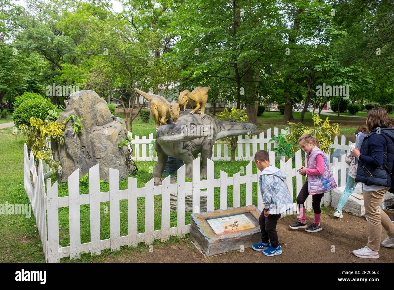 Adults and kids staring the animatronic or robotic dinosaurs in a park Stock Photo