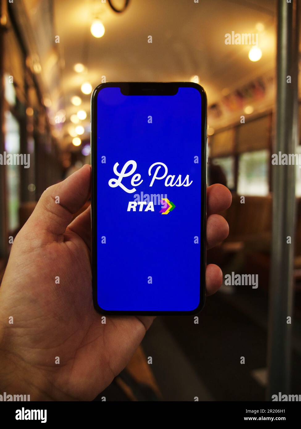 A person holding a smartphone, displaying a le pass rta logo on the screen Stock Photo