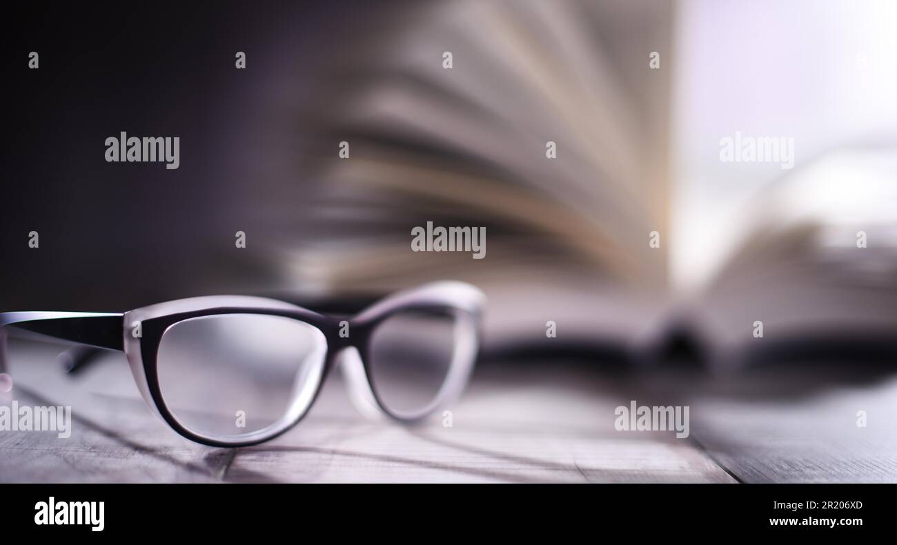 Composition with glasses and open book on the table Stock Photo