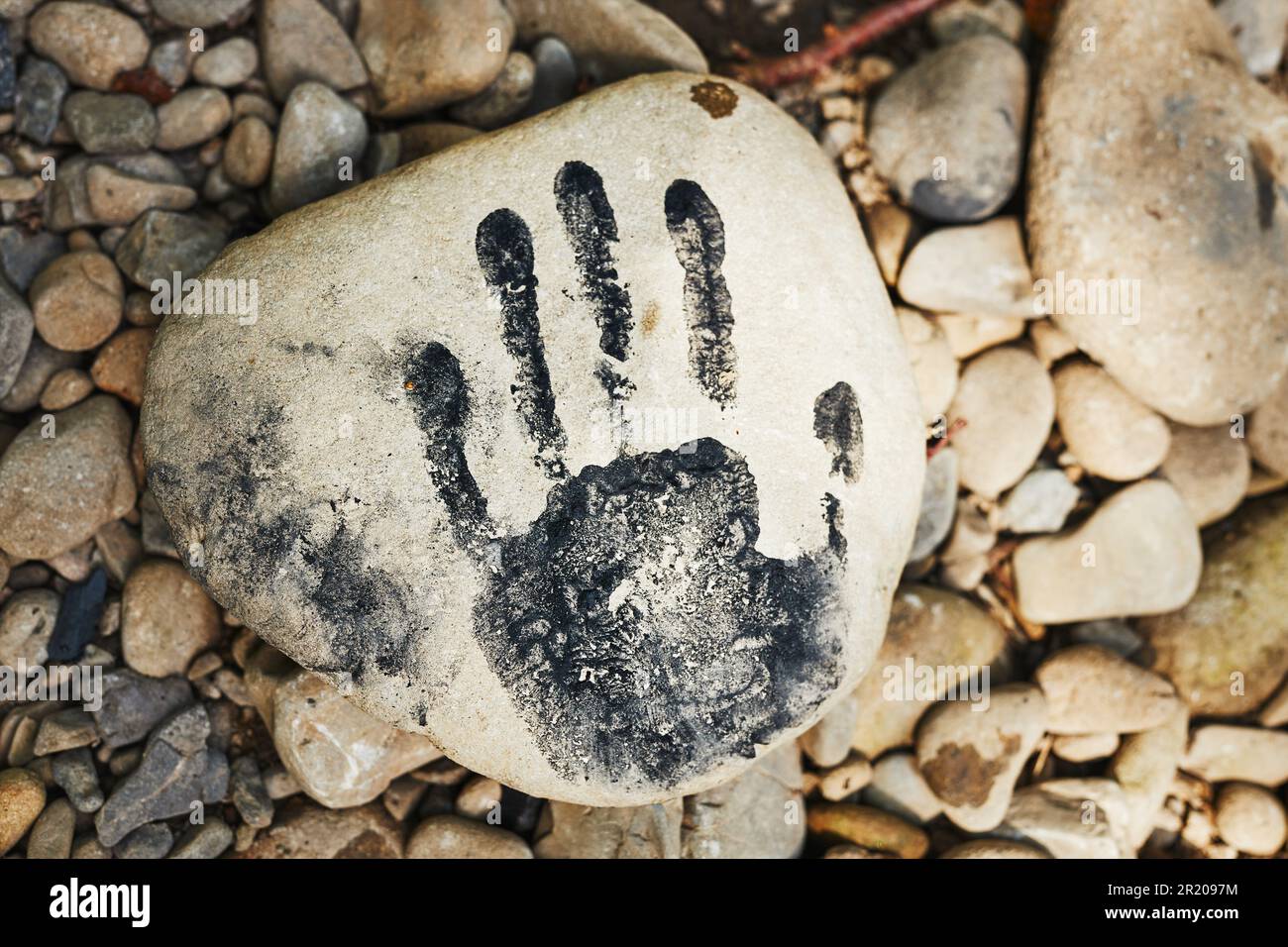 Hand print on stone. Human imprint. Close up of handmark. Sign left by human. Black print. Identity concept Stock Photo
