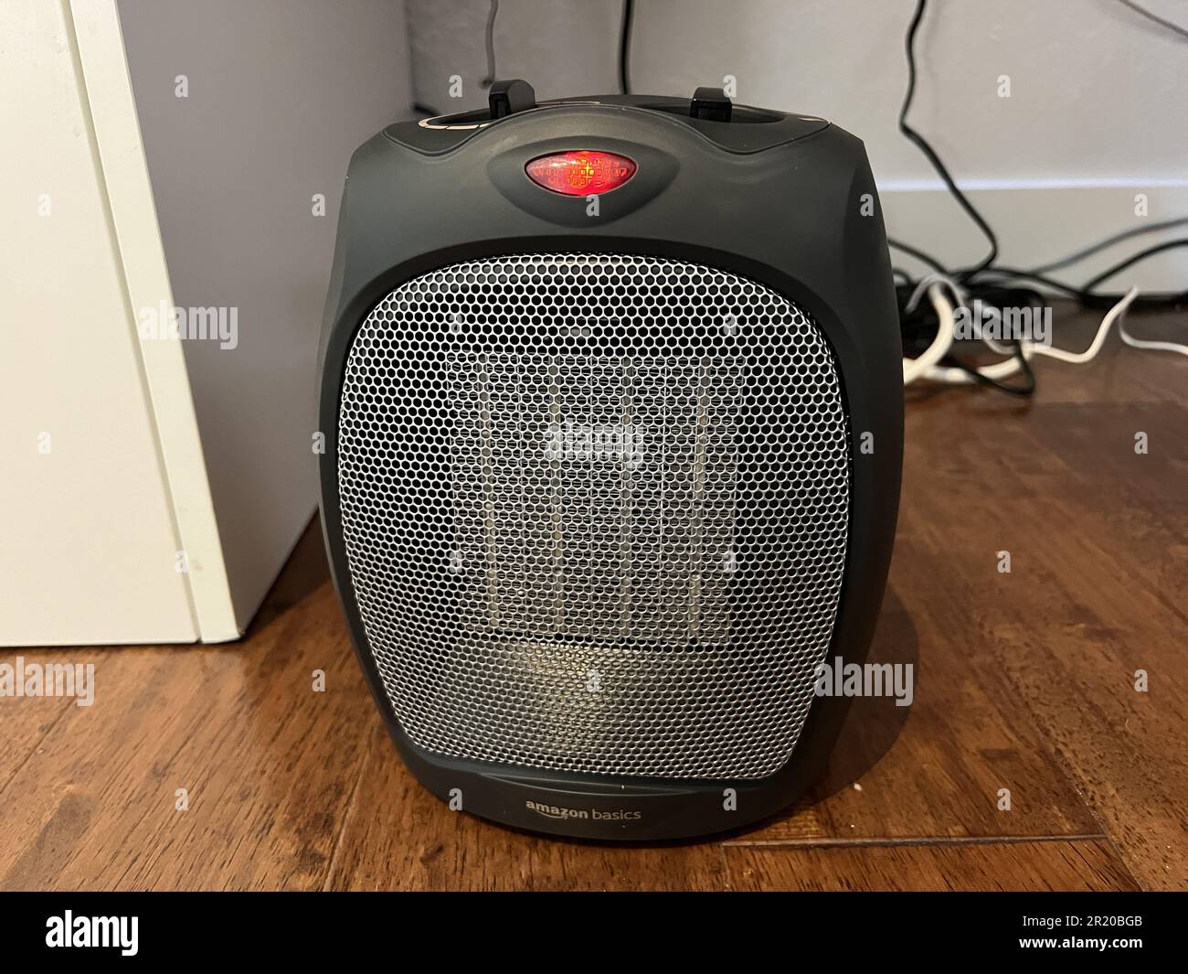 USA. 10th Nov, 2022. Frontal shot of an Amazon Basics 1500W Premium  Portable Oscillating Ceramic Tower Space Heater, resting on wood-plank  flooring with cords and white furniture and walls in the background,