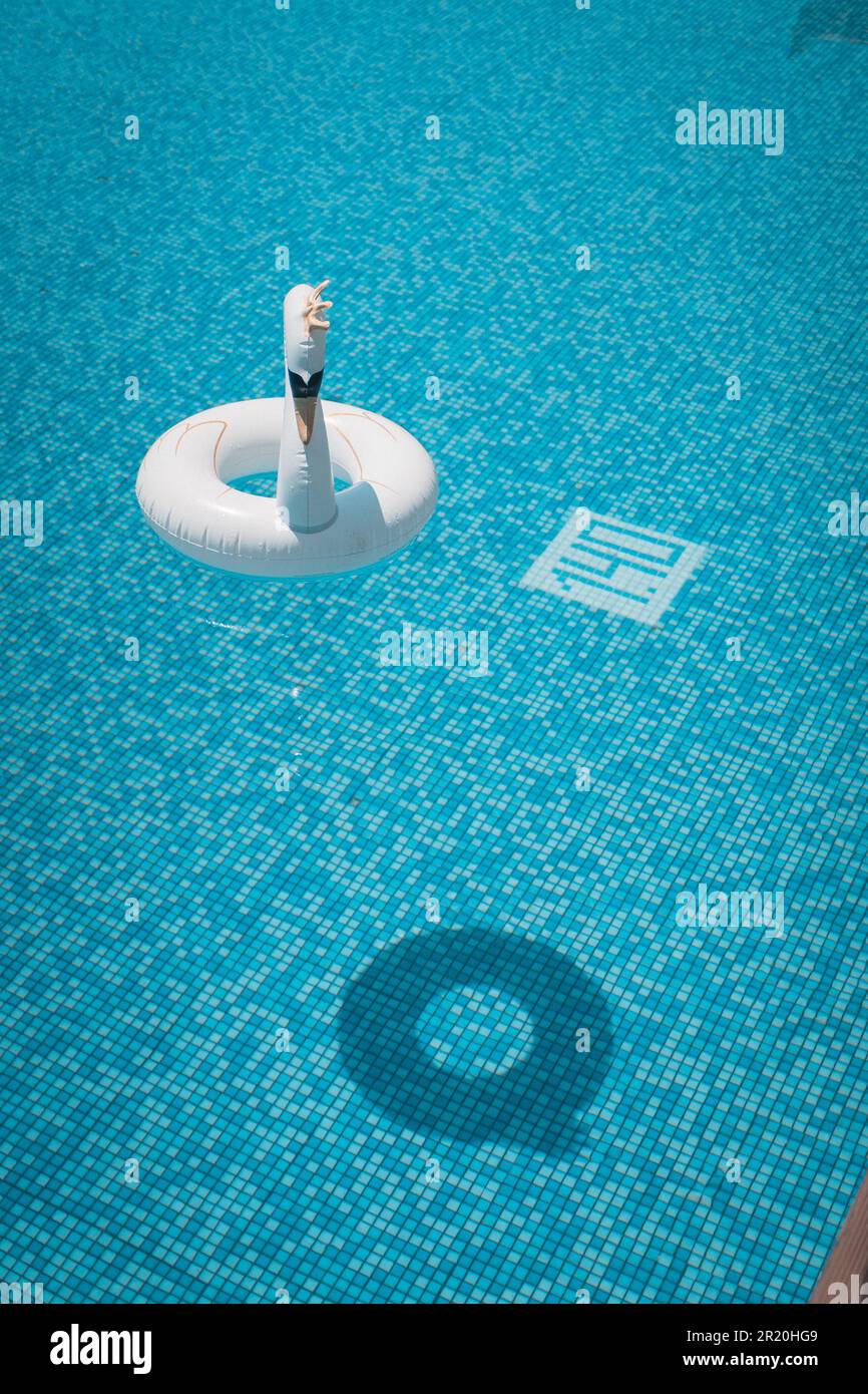 An Inflatable swan with a crown floating on the pool in the summer