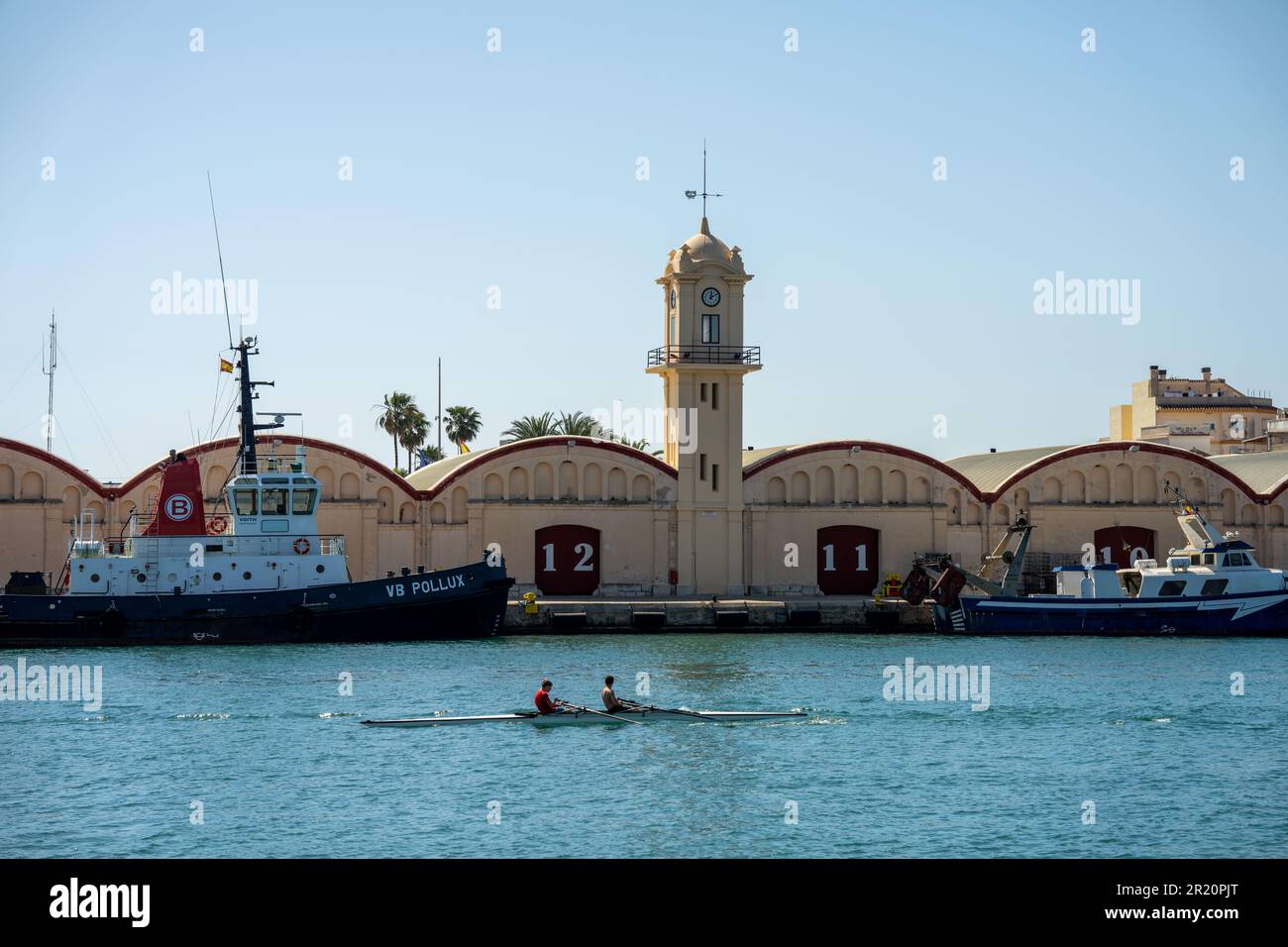 canoe in the harbor with a fishing boat in the background and buildings with the numbers 12 and 11 Stock Photo