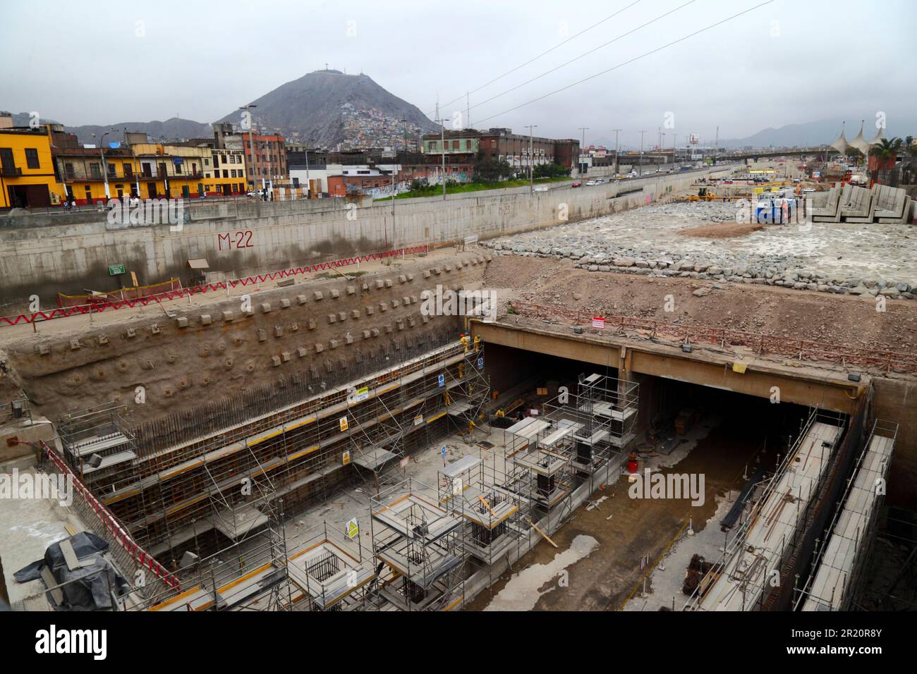 Construction site of tunnel under the River Rimac for a new motorway and Yellow Line Via Expresa bus route, Lima, Peru. The tunnel runs for 1.8km under the River Rimac, which was diverted to allow construction to take place. Works started in January 2012 and took 6 years, the tunnel opened in June 2018. The Brazilian company OAS built the tunnel. The conical hill in the background is Cerro San Cristobal. Stock Photo
