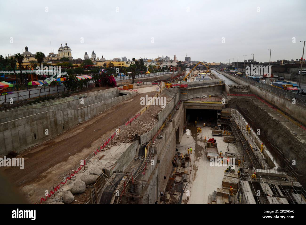 Construction site of tunnel under the River Rimac for a new motorway and Yellow Line Via Expresa bus route, Lima, Peru. The tunnel runs for 1.8km under the River Rimac, which was diverted to allow construction to take place. Works started in January 2012 and took 6 years, the tunnel opened in June 2018. The Brazilian company OAS built the tunnel. The 2 yellow towers in the background are part of San Francisco church in the historic centre. Stock Photo