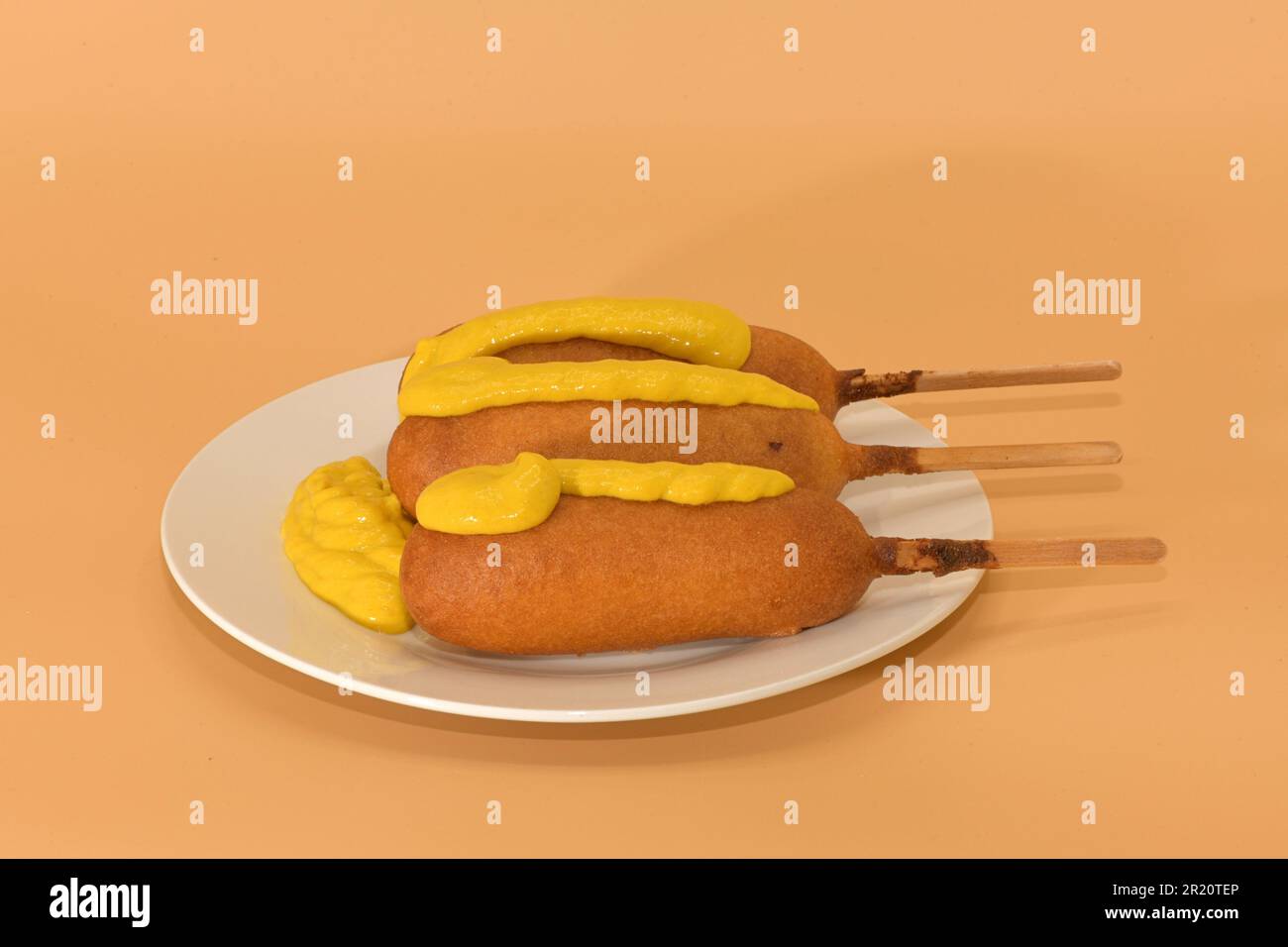 Freshly prepared corndogs on a plate with mustard. Stock Photo