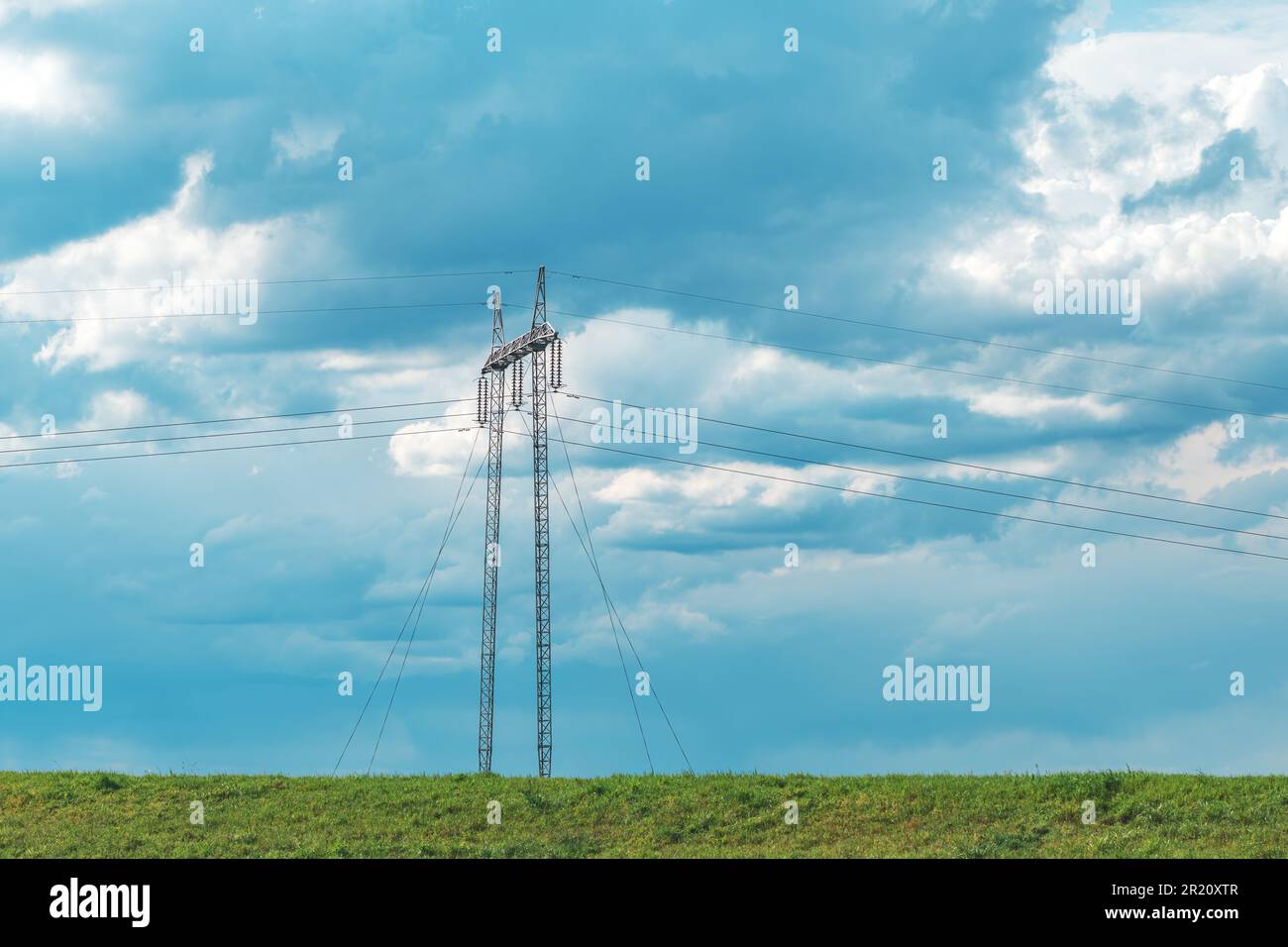 Electricity transmission tower line with overhead wires in countryside landscape on overcast cold spring day Stock Photo