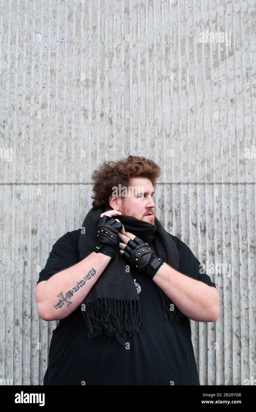The influencer Drachenlord with a dark beard wearing a black shirt and  black leather gloves in front of a wall Stock Photo - Alamy