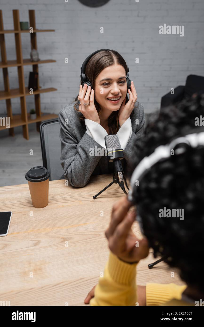 happy broadcaster adjusting headphones during interview with