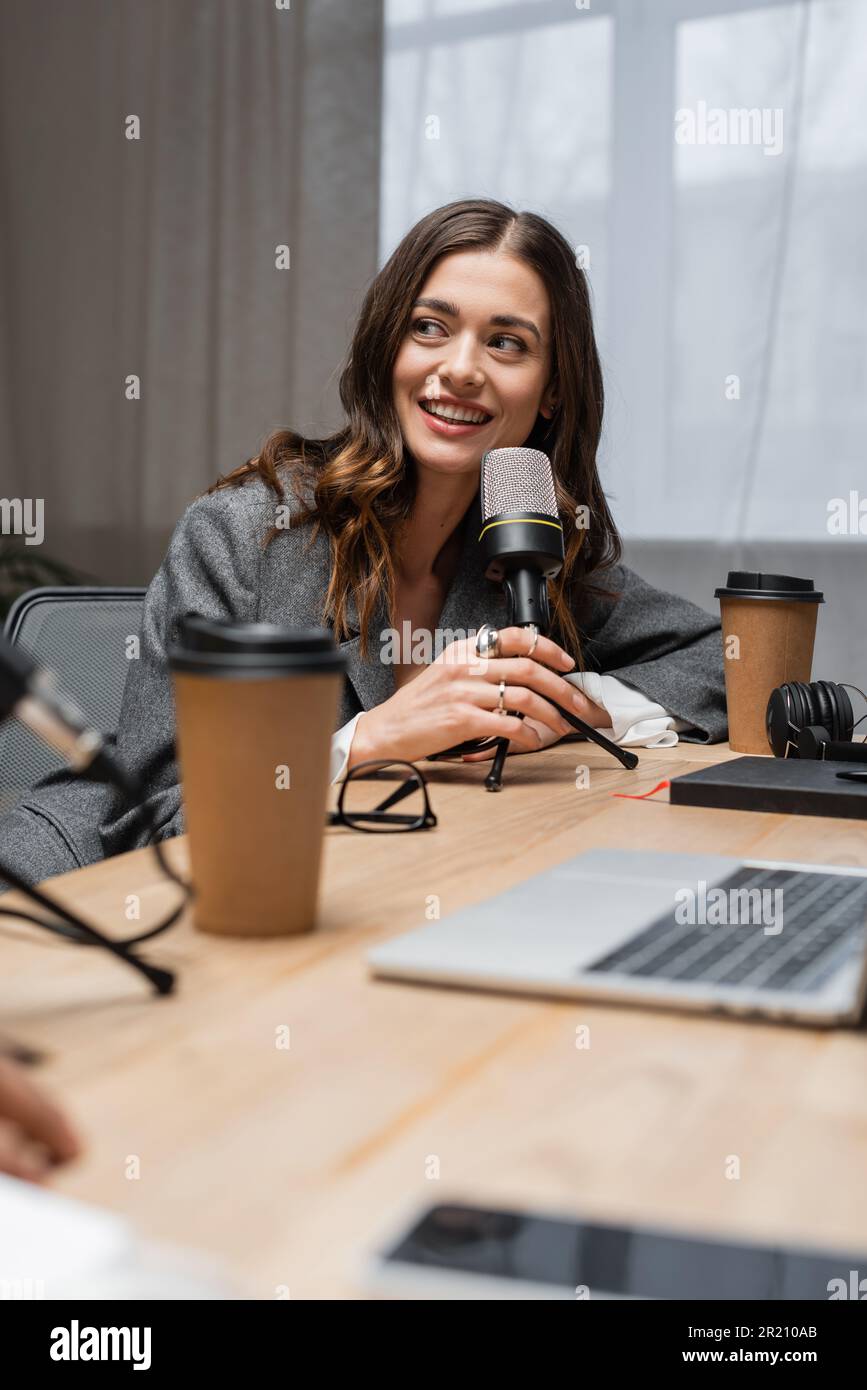 happy and charming radio host looking away while talking in ...