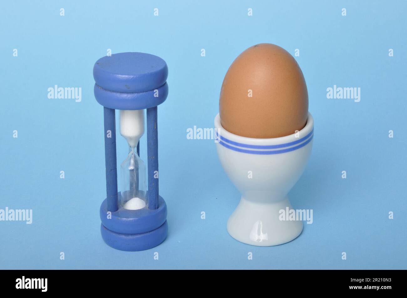 Boiled egg and hourglass on a blue background Stock Photo
