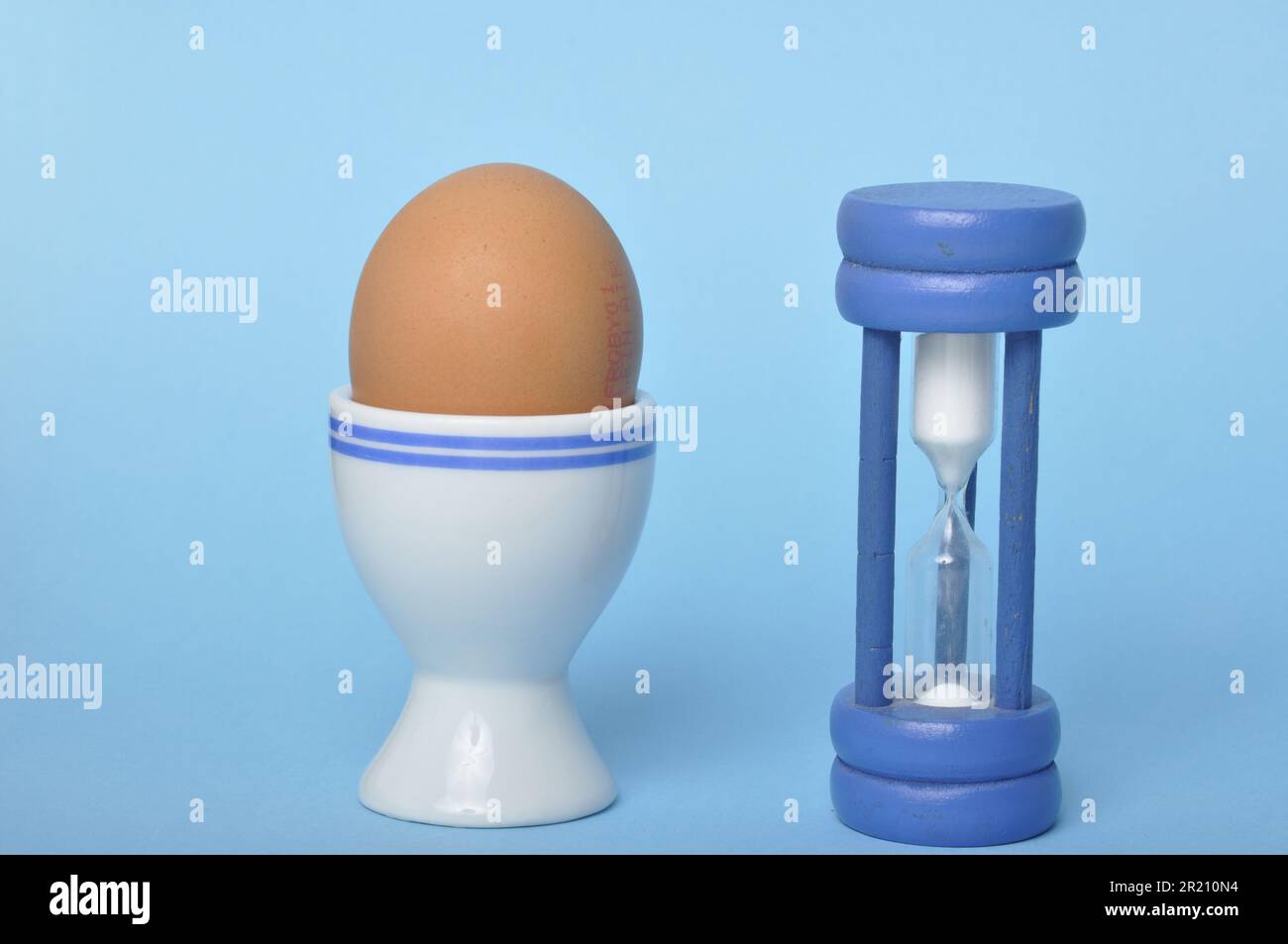 Boiled egg and hourglass on a blue background Stock Photo