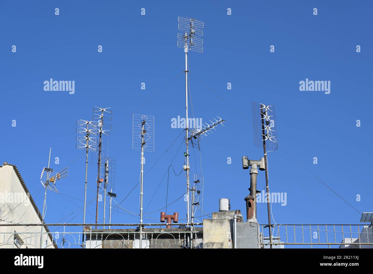 Various antennas on the roof of a residential apartment building, installation for communication and media such as tv, internet, smartphone and radio, Stock Photo