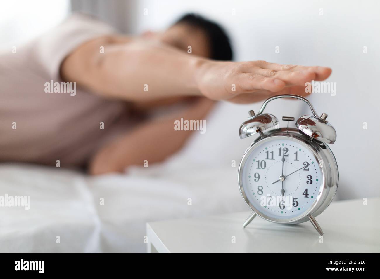 Man hand turning off alarm clock waking up at morning Stock Photo