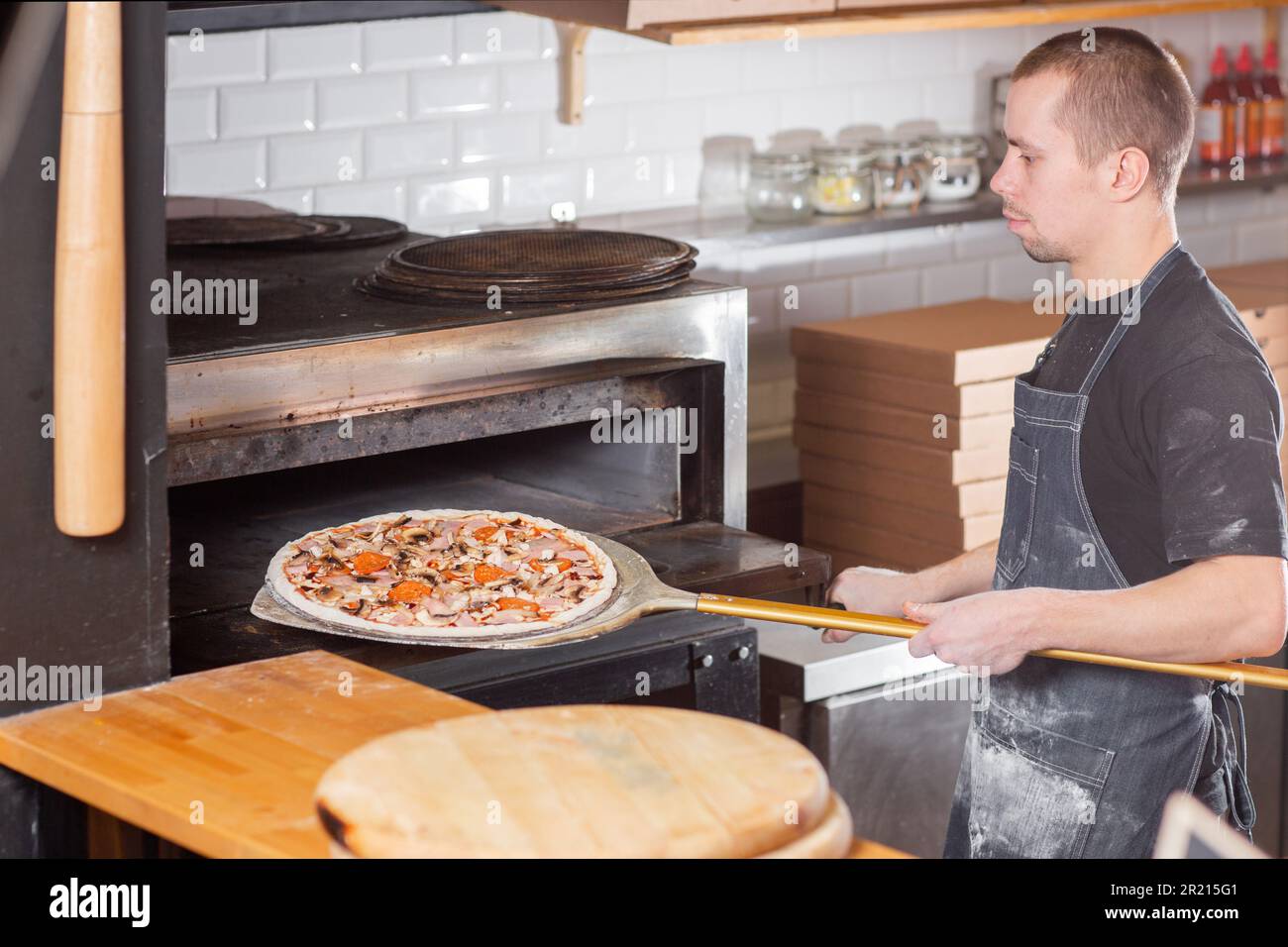 The chef prepares pizza. Raw pizza ready to bake. Cook in a blue apron