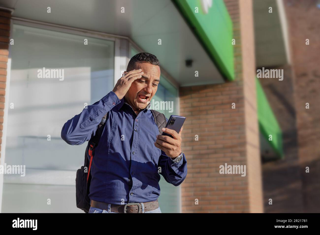Young latin man looking at his mobile phone with a surprised face. Stock Photo