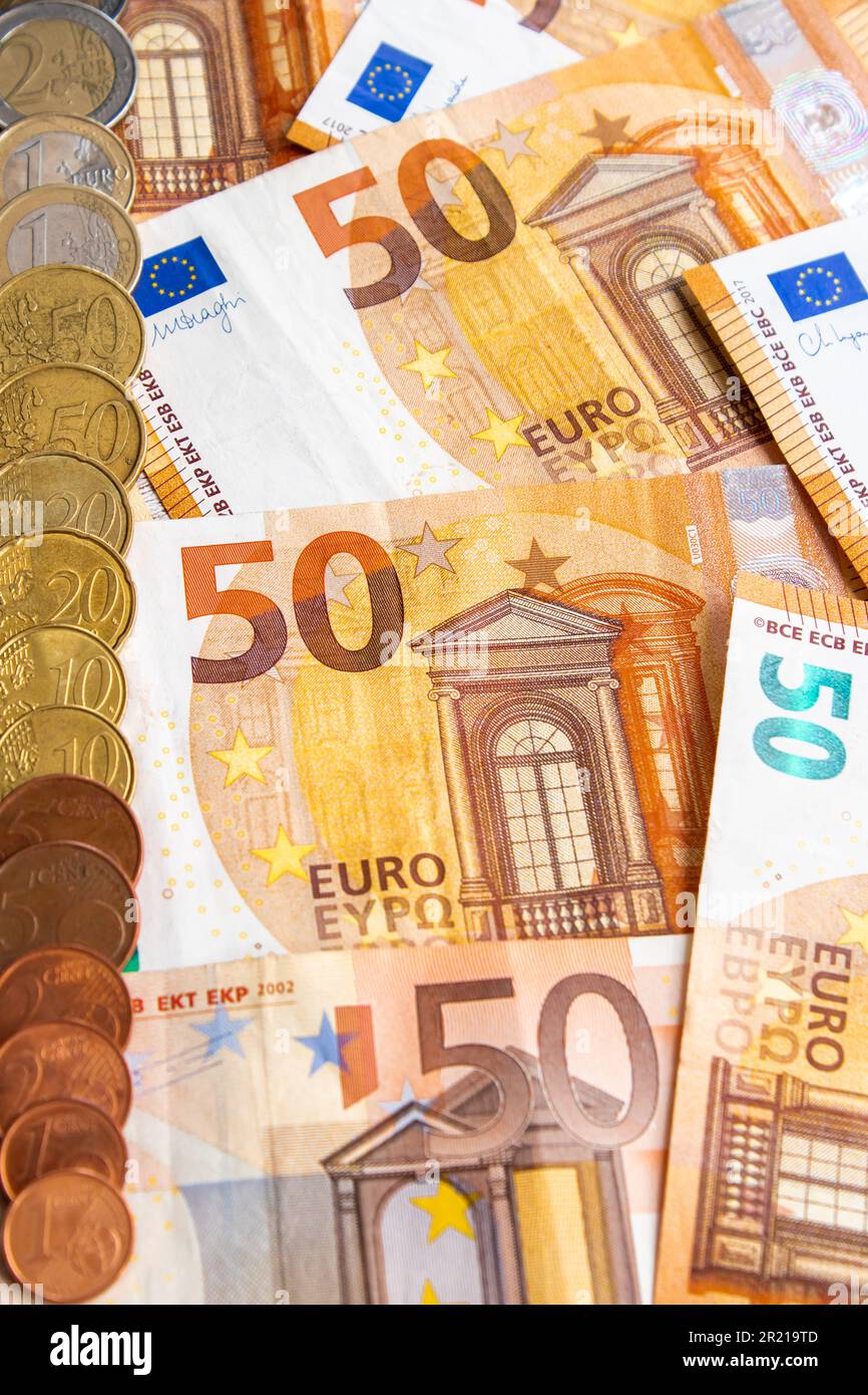 pile of fifty-euro bills and a row of euro coins on the right side of the image. vertical photograph Stock Photo