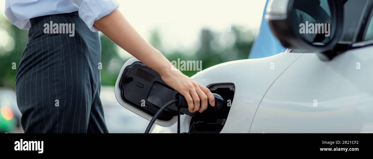 Closeup focus hand insert EV charger to electric vehicle at public