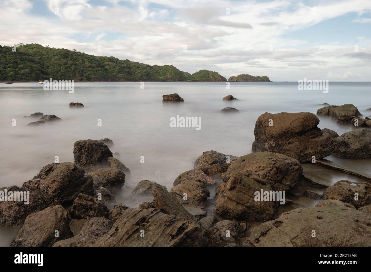 Rocks on ocean beach with silky sea water background Stock Photo
