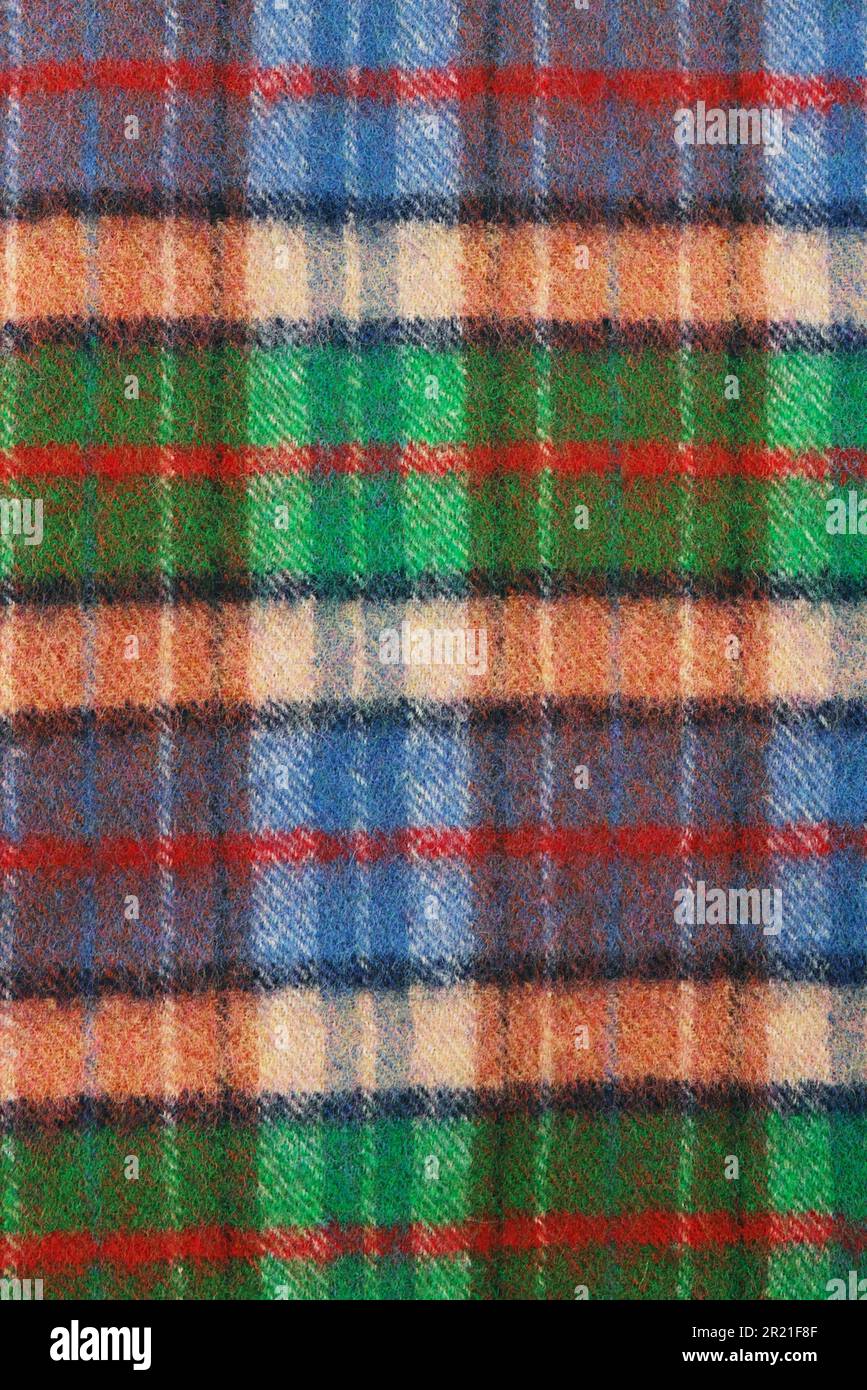 Wool plaid texture. Soft and warm folded alpaca wool blanket. Green and orange wool plaid texture macro shot. Wool coat Stock Photo