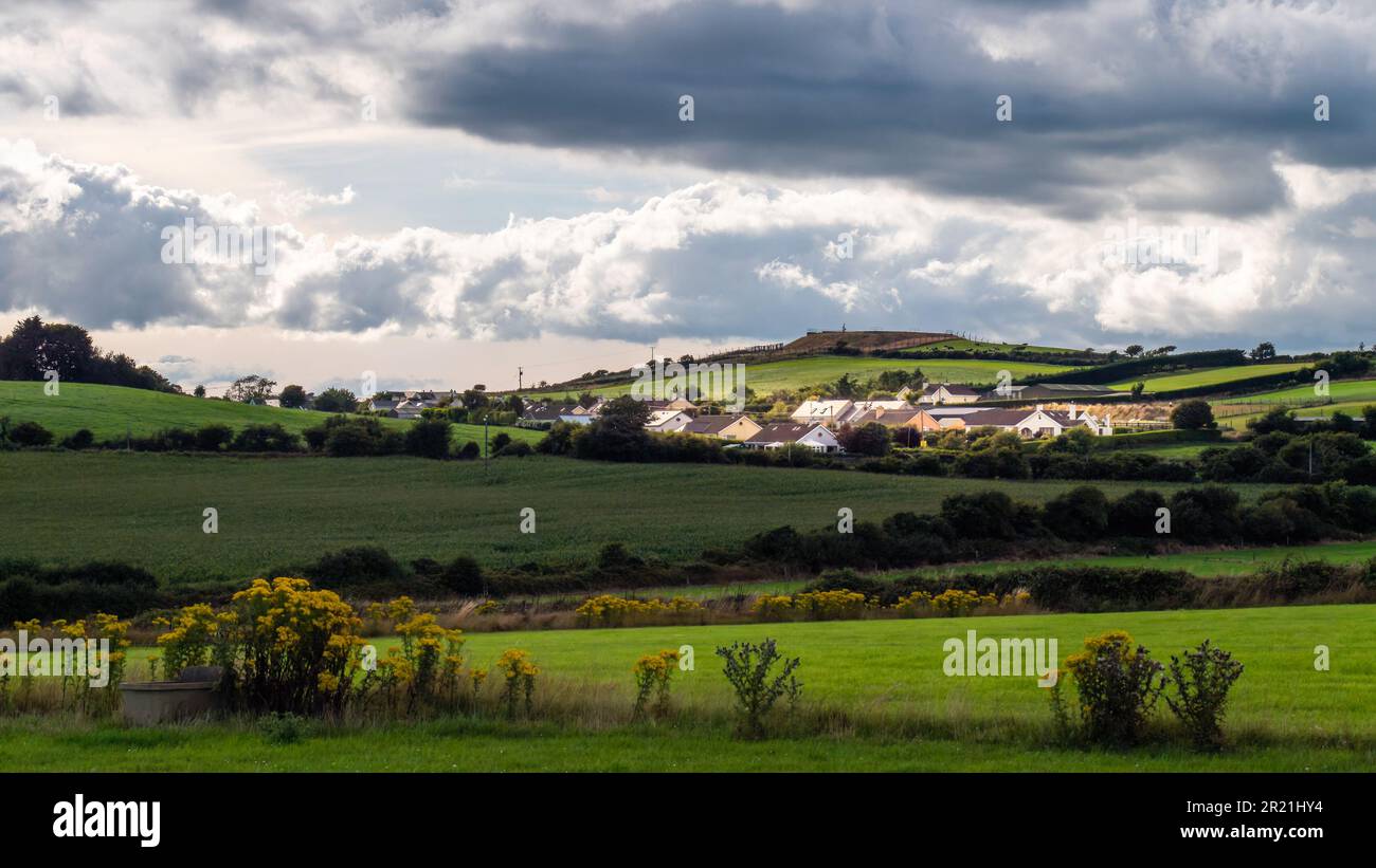 Sky with cumulus clouds over a Irish village on evening. Irish settlement in County Cork, landscape. European countryside, rustic landscape. Green fie Stock Photo