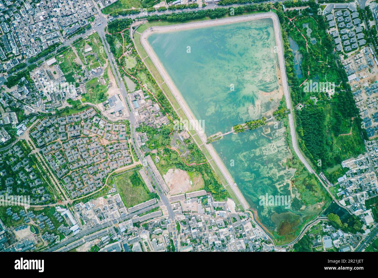 An aerial view of a small city surrounded by lush green vegetation and ...