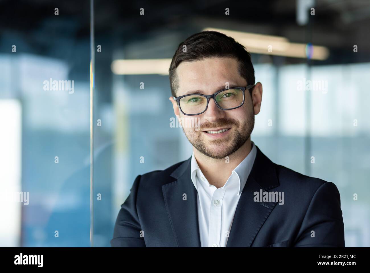 Portrait of a young male accountant, businessman, office worker looking at the camera and smiling. It is located in the office center. Close-up photo. Stock Photo