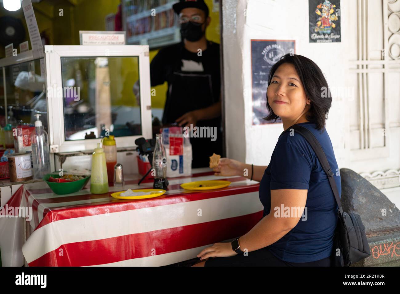 Mexico City, Mexico, May 07, 2023: Asian girl eating taco in a Taqueria Stock Photo