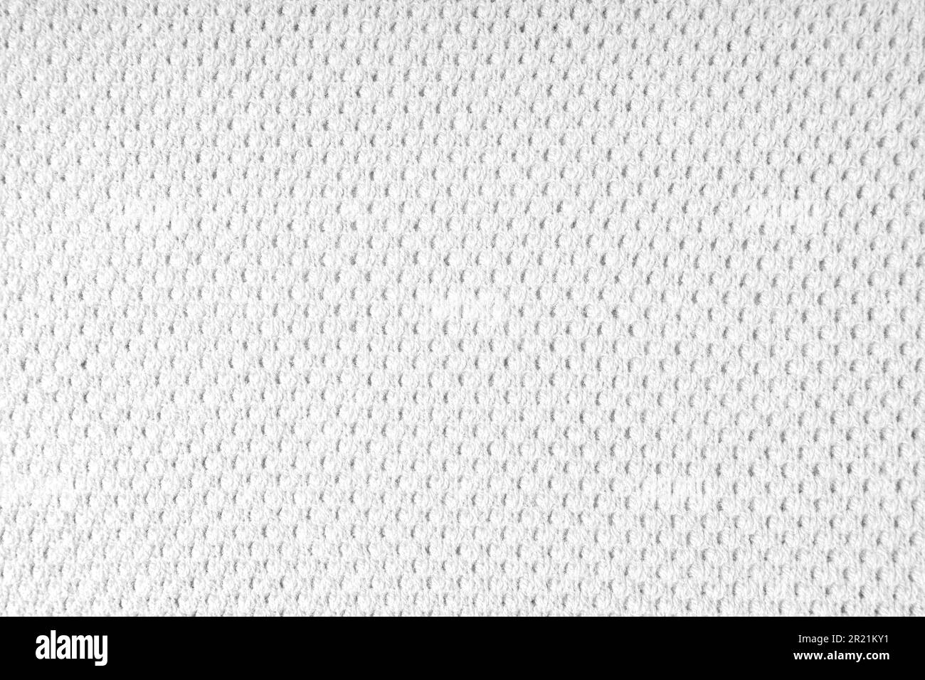 Close up background of knitted wool fabric with dots pattern. White color wool knitwear texture. Openwork abstract knitted jersey. Fabric abstract bac Stock Photo
