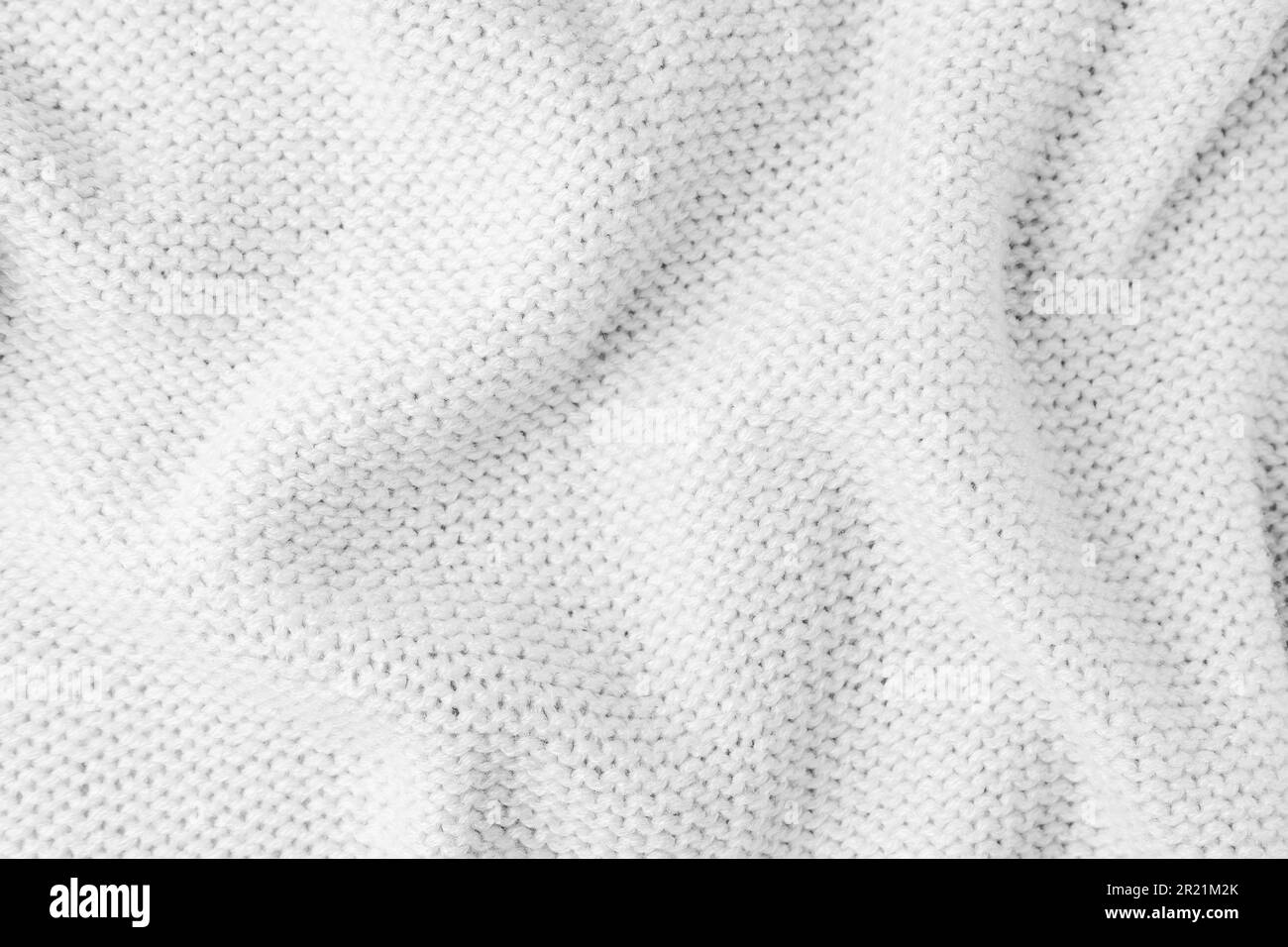 Close up background of knitted wool fabric made of viscose yarn. White color crumpled knitting wool knitwear texture. Abstract knitted wrinkled jersey Stock Photo