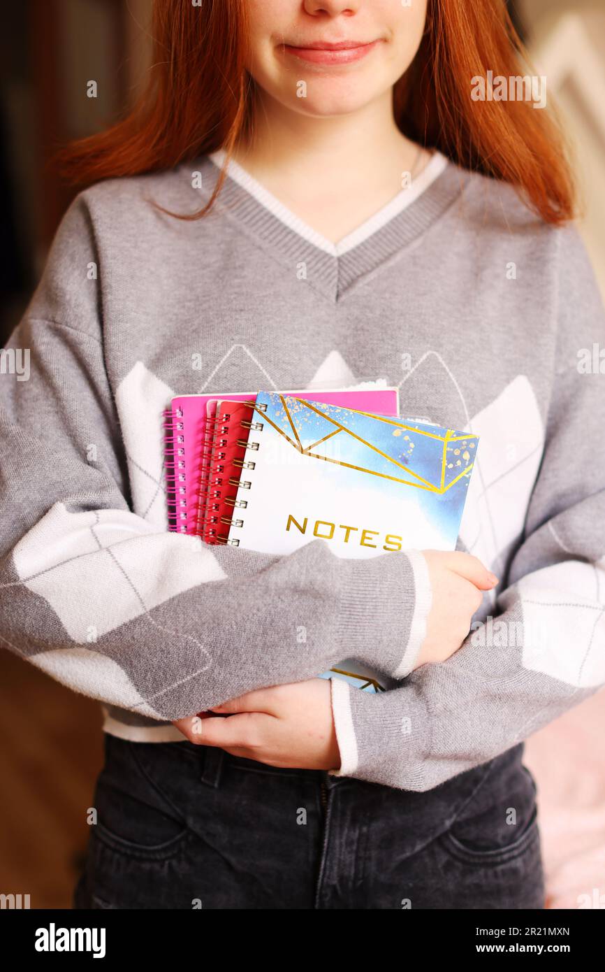 Image of young beautiful student girl smiling and holding exercise books  Stock Photo