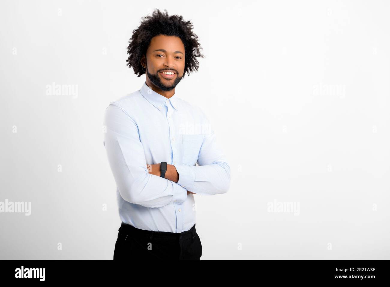 Handsome curly man looking at camera standing with arms crossed ...