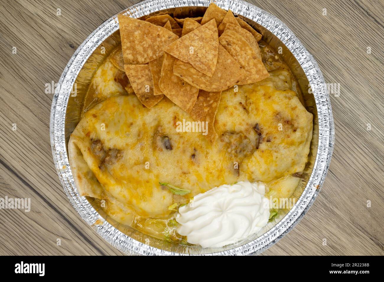 Overhead view of to go order of a chile verde wet burrito with chips