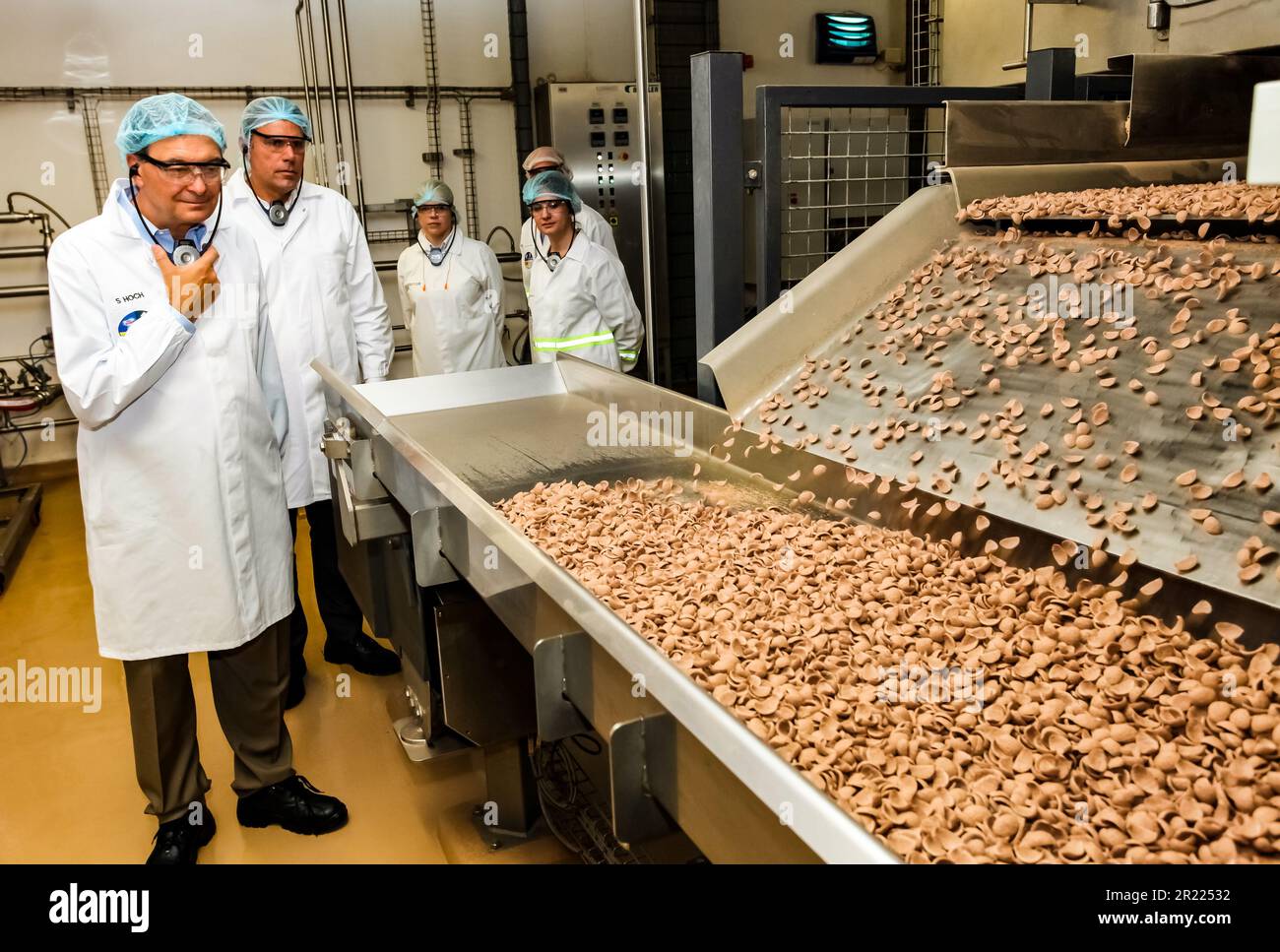 A group of manufacturing workers observing a production line in a chocolate factory Stock Photo