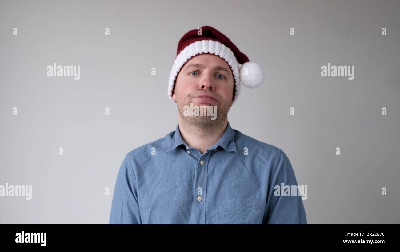 The sad and sorrowful European young man in a New Year's hat looks gloomily into the camera. Disappointments in the New Year celebration Stock Photo